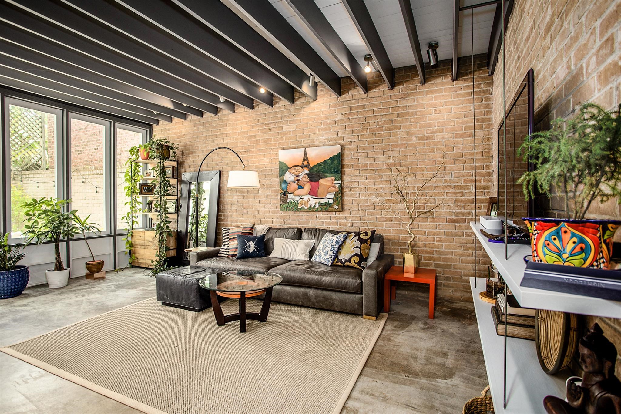 1942 Indiana Street Houston, TX 77019 - Photo 2 of 40 Step through the front door to a bright open living room, with exposed brick walls and beams overhead. Door to access the backyard is to the left of the windows (not pictured here).
