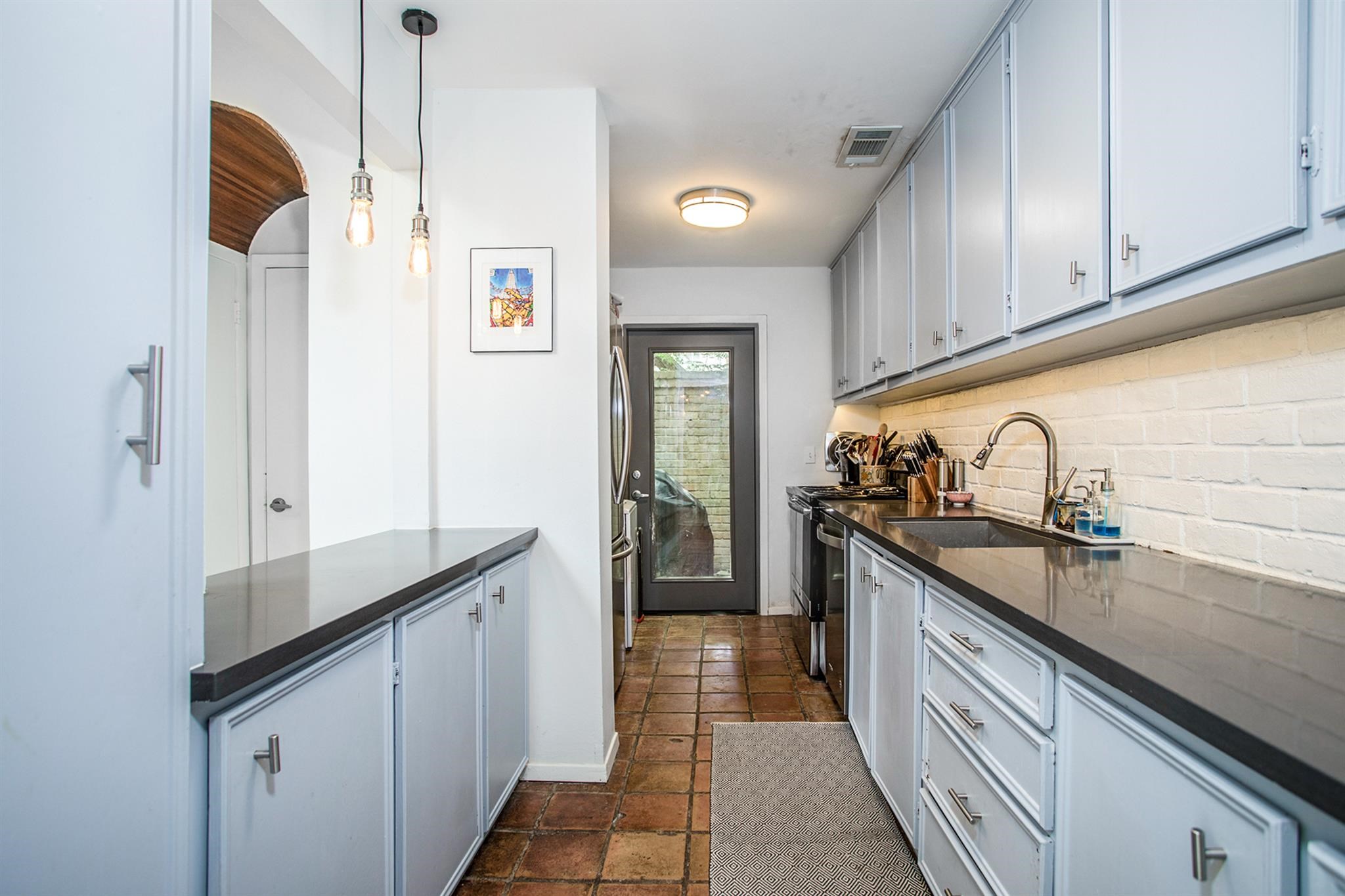 1942 Indiana Street Houston, TX 77019 - Photo 7 of 40 Recently updated kitchen with quartz counters, stainless steel appliances, under cabinet LED lighting, and a large undermount sink. Glass door leads to a private court yard.