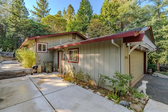 a backyard of a house with plants and trees with wooden fence