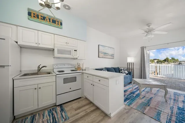 a kitchen with a sink dishwasher a stove and white cabinets with wooden floor