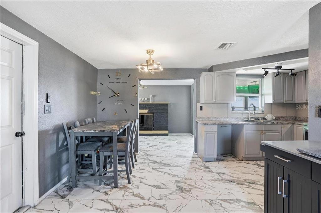 3208 Kilburn Road Holiday, FL 34691 - Photo 3 of 17 a kitchen with kitchen island a chandelier dining table cabinets and appliances