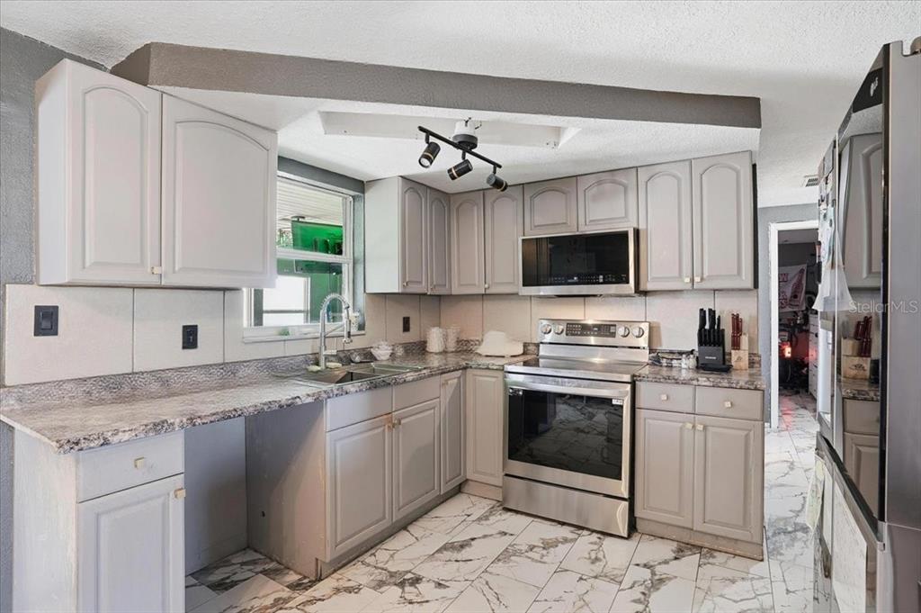 3208 Kilburn Road Holiday, FL 34691 - Photo 4 of 17 a kitchen with stainless steel appliances granite countertop a stove sink microwave and refrigerator