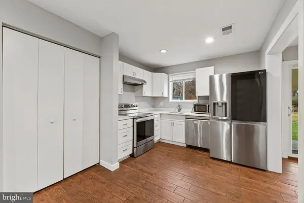 a kitchen with a refrigerator stove and white cabinets