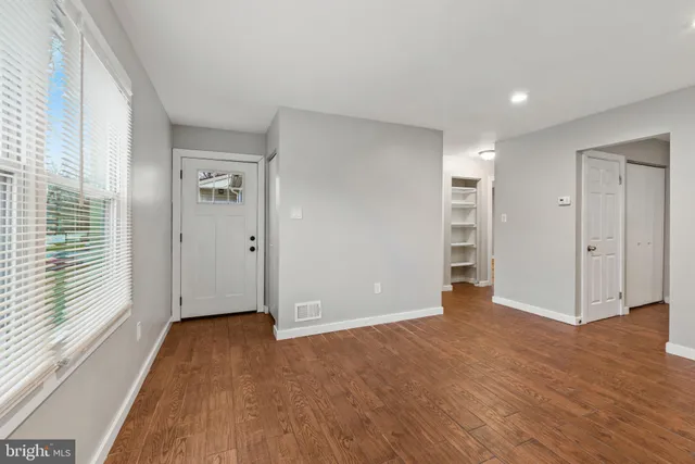a view of empty room with wooden floor and window