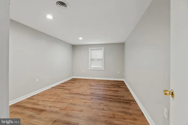an empty room with wooden floor and window