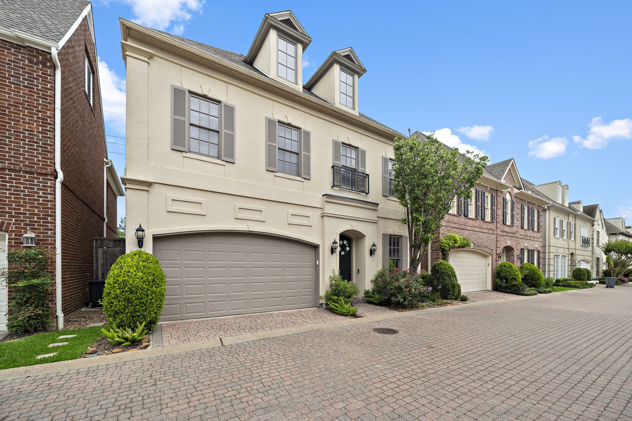 This is a charming two-story single family home with a classic design, featuring a two-car garage and a small front garden. The exterior is well-maintained, with neutral tones and elegant window shutters, creating a welcoming curb appeal.