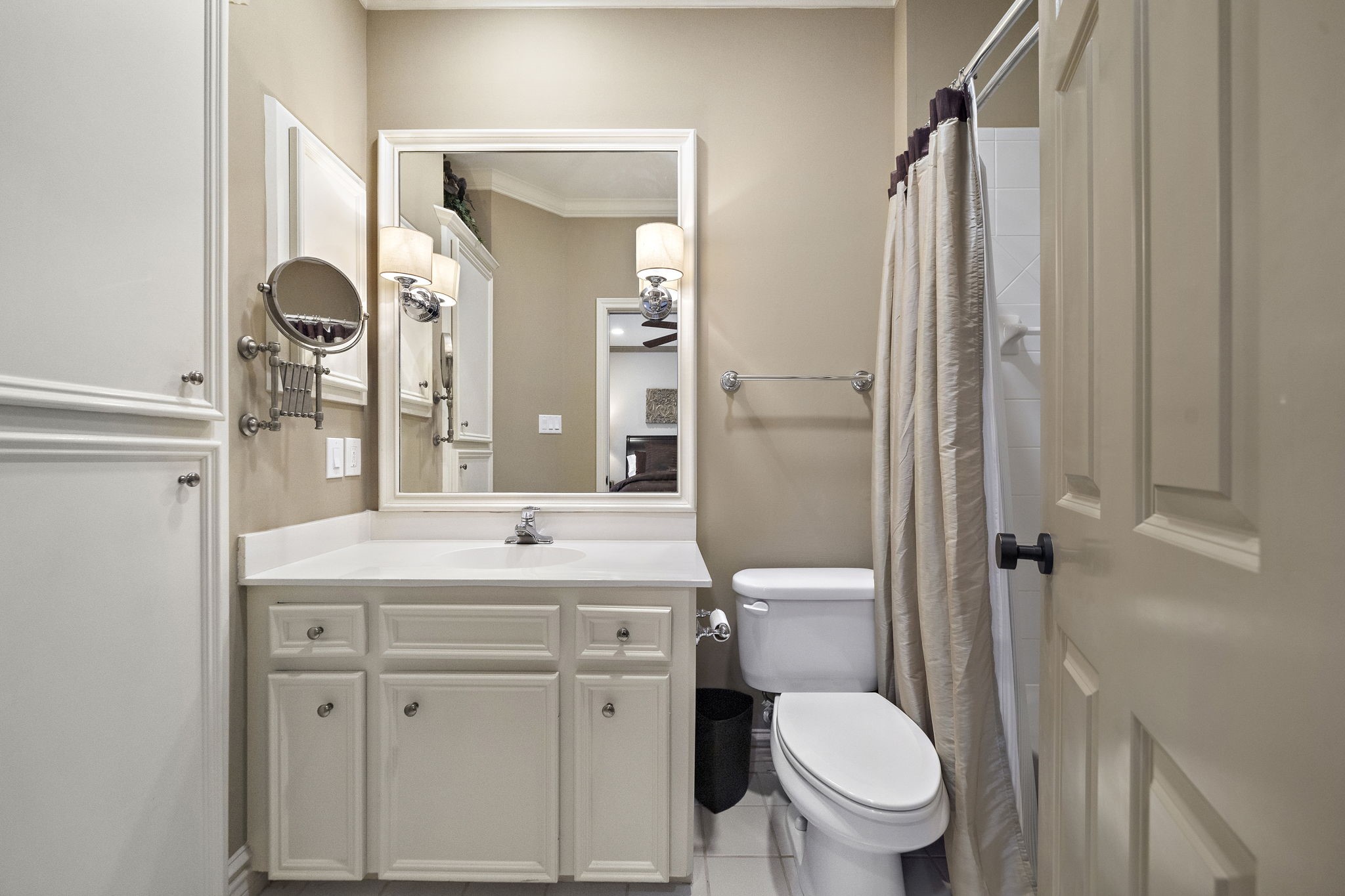 1229 Ripple Creek Drive Houston, TX 77057 - Photo 19 of 49 This is a compact, well-lit bathroom featuring a single vanity with ample storage, a large mirror, and a toilet. The shower is enclosed with a curtain, and the neutral color scheme adds a clean, welcoming feel.