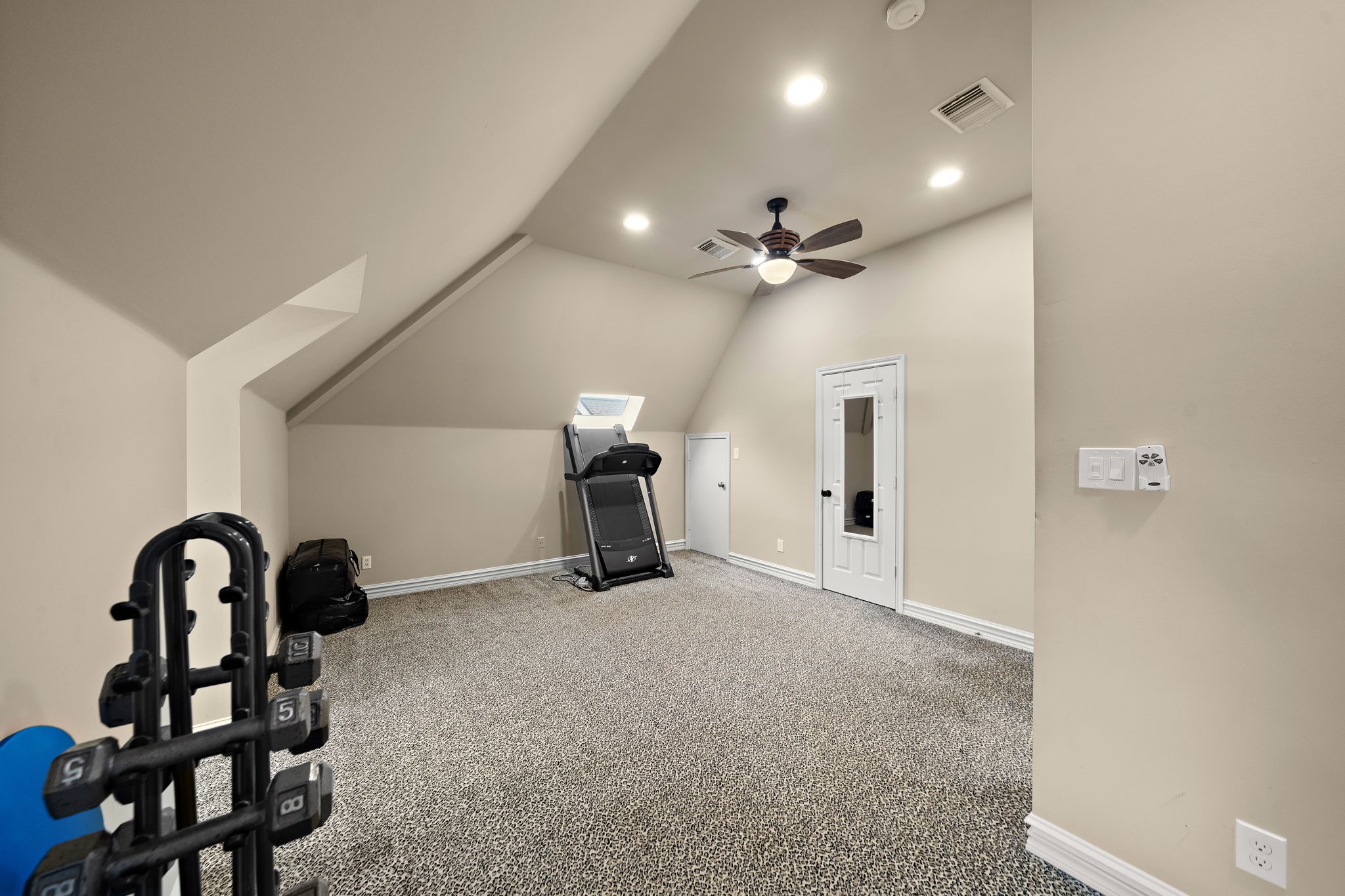1229 Ripple Creek Drive Houston, TX 77057 - Photo 30 of 49 This spacious room features a sloped ceiling with recessed lighting and a ceiling fan. Equipped with a treadmill and dumbbells, it's ideal for a home gym. The neutral walls and carpet create a cozy, versatile space.