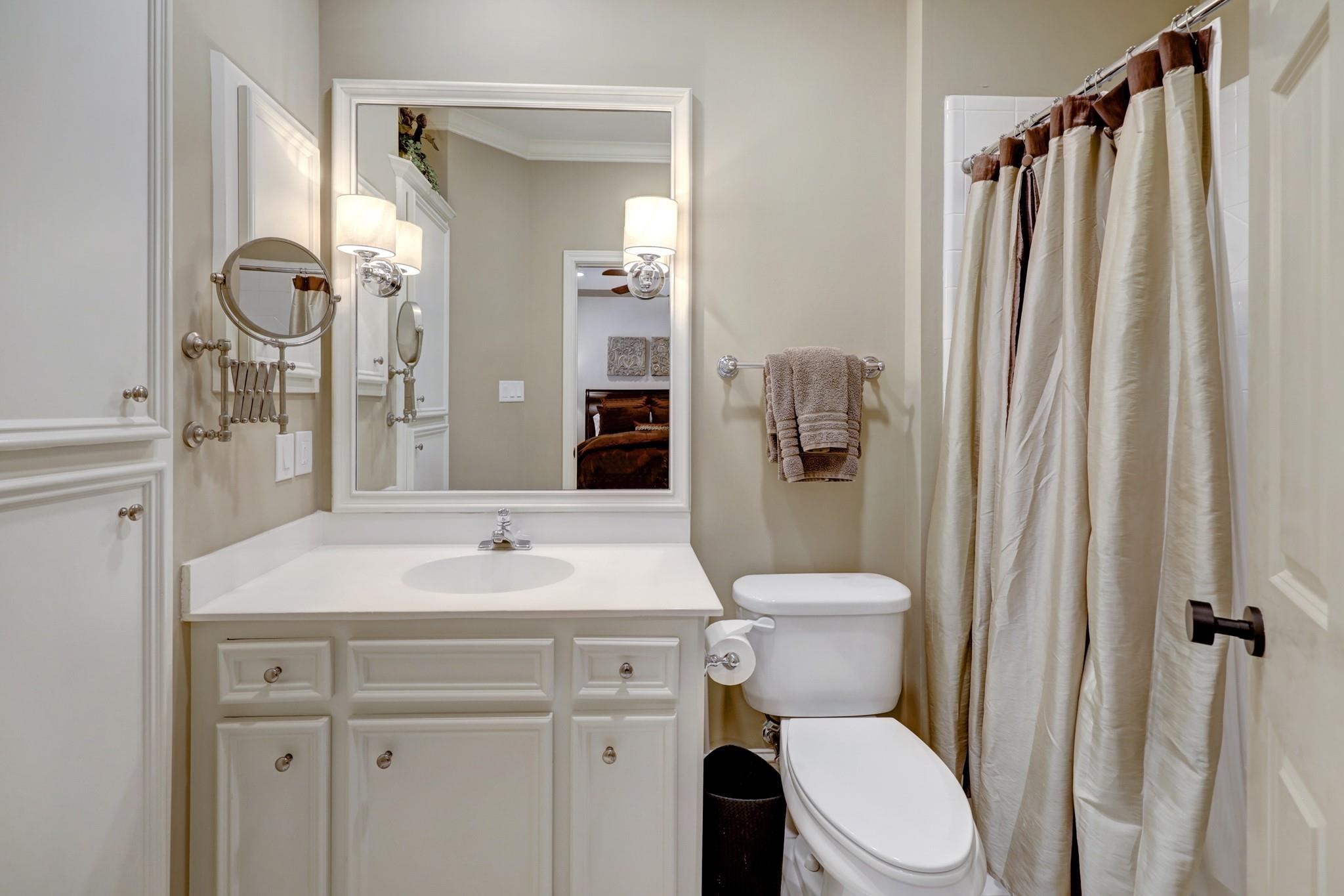 1229 Ripple Creek Drive Houston, TX 77057 - Photo 38 of 49 This spacious bedroom features a vaulted ceiling, a large bed with plush bedding, and a cozy seating area by the window. The room is elegantly decorated with neutral tones, modern lighting, and a sleek entertainment unit with a mounted TV.