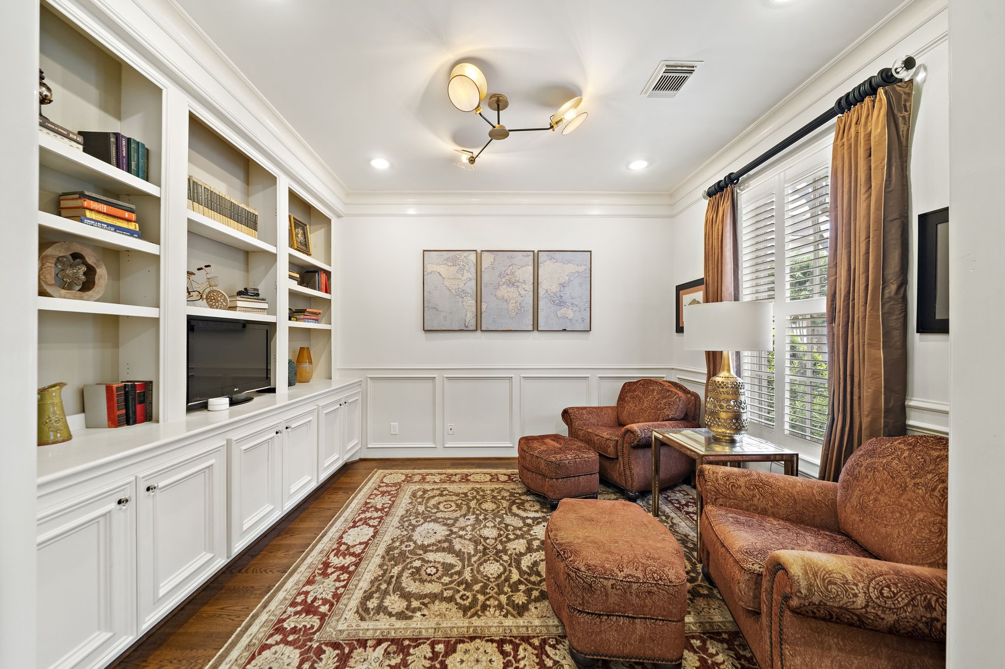 1229 Ripple Creek Drive Houston, TX 77057 - Photo 4 of 49 This cozy study features elegant built-in shelves, a large window with rich drapes, and comfortable seating. It has a warm, inviting atmosphere with wood flooring and a decorative area rug, ideal for reading or relaxation.