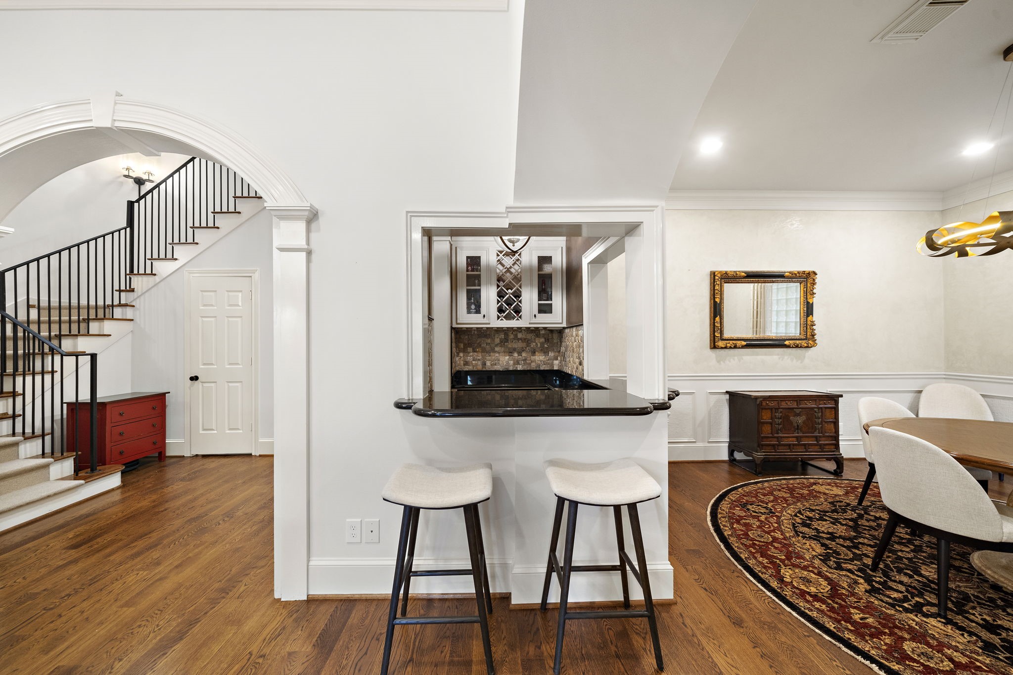 1229 Ripple Creek Drive Houston, TX 77057 - Photo 7 of 49 This inviting space features hardwood floors and a cozy dining area with elegant lighting. An archway leads to a staircase, and a breakfast bar connects to a stylish kitchen. Classic design elements and neutral tones enhance the warmth and charm.