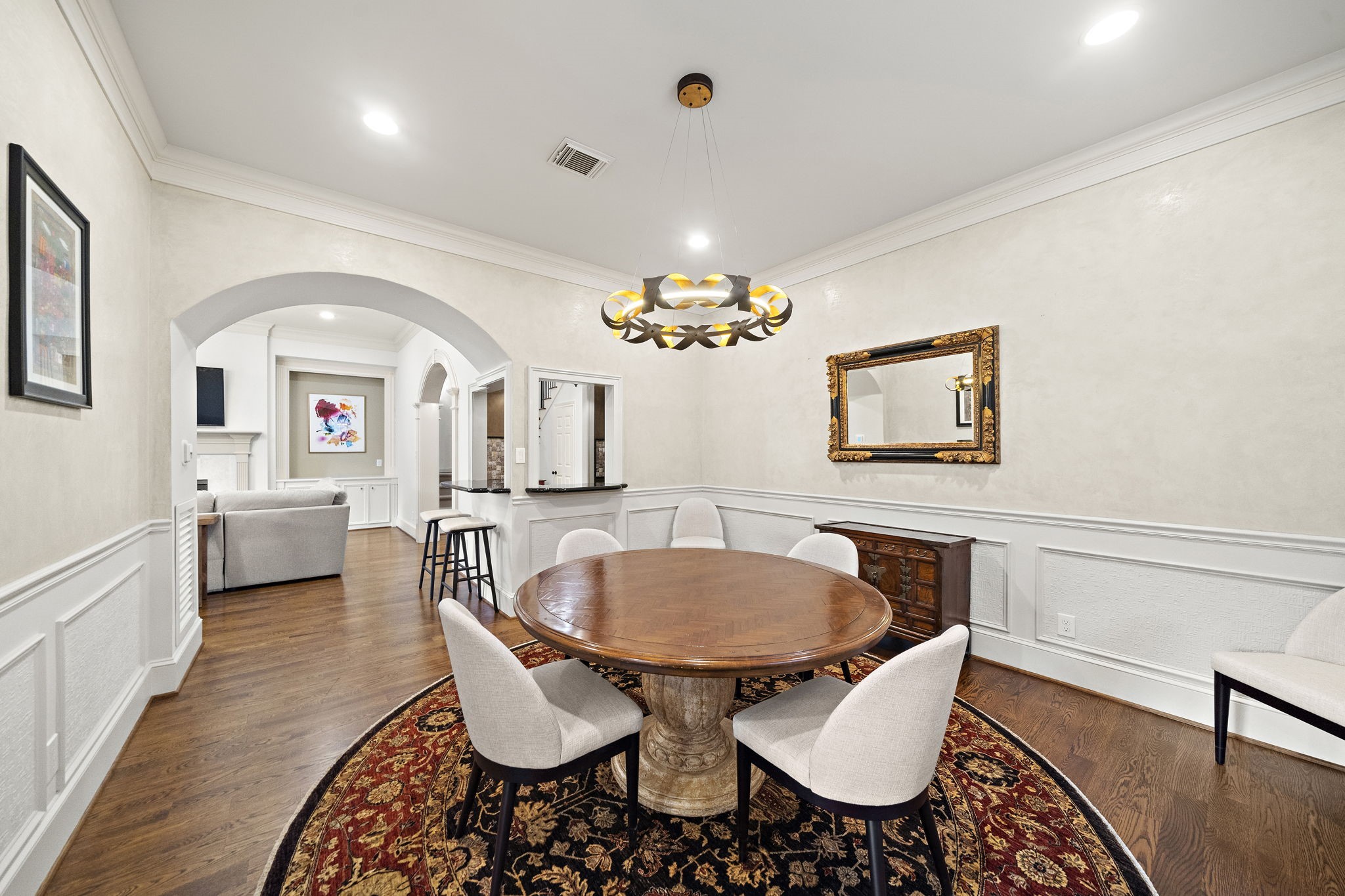 1229 Ripple Creek Drive Houston, TX 77057 - Photo 9 of 49 This elegant dining room features a round wooden table, contemporary chairs, and a stylish chandelier. It opens to a cozy living area with arched entryways and warm hardwood floors, creating a seamless flow for entertaining.
