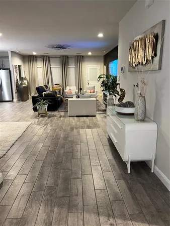 a living room with couches and kitchen view with wooden floor