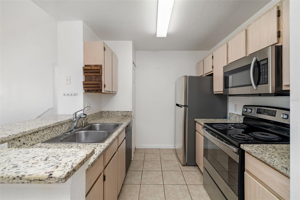 8933 Manor Loop, Unit 205 Lakewood Ranch, FL 34202 - Photo 15 of 76 a kitchen with stainless steel appliances granite countertop a sink stove and refrigerator