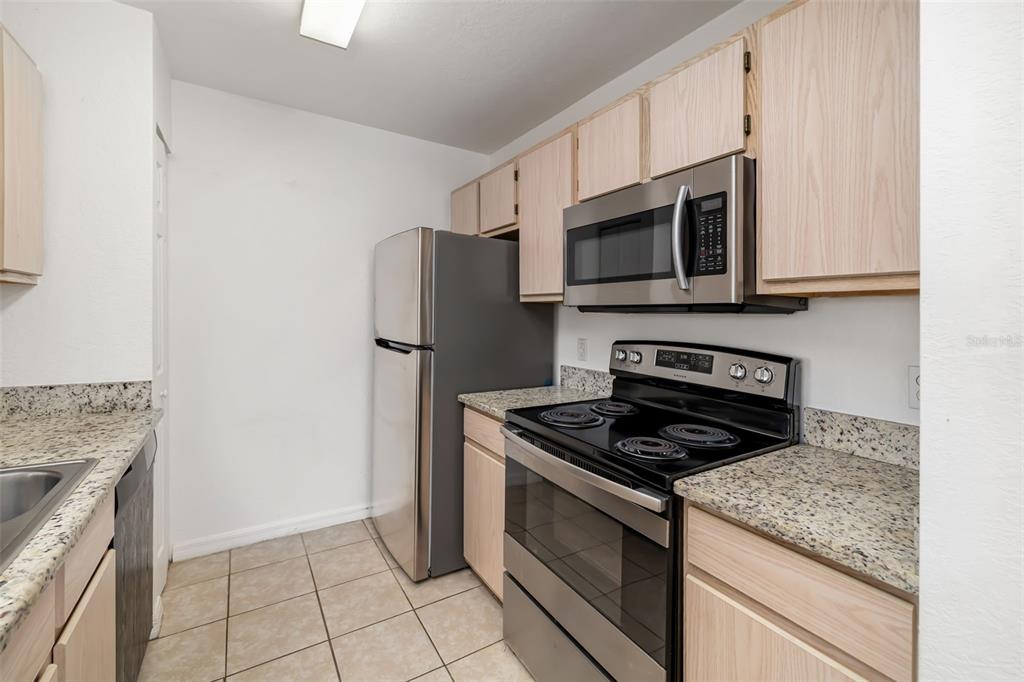 8933 Manor Loop, Unit 205 Lakewood Ranch, FL 34202 - Photo 16 of 76 a kitchen with granite countertop cabinets stainless steel appliances and a counter space