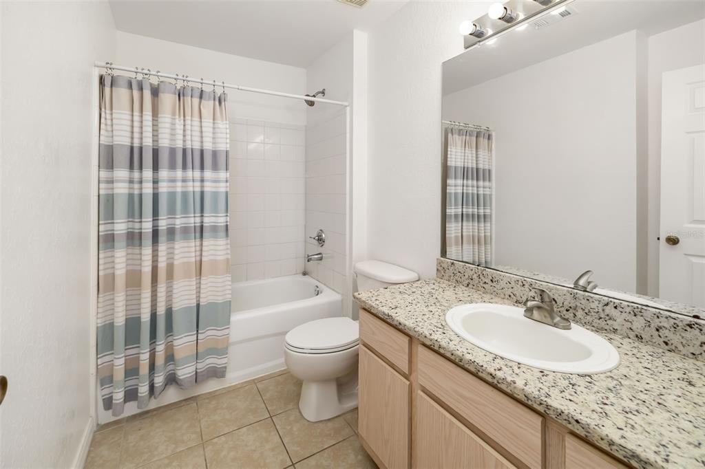 8933 Manor Loop, Unit 205 Lakewood Ranch, FL 34202 - Photo 25 of 76 a bathroom with a granite countertop sink a toilet a mirror and shower