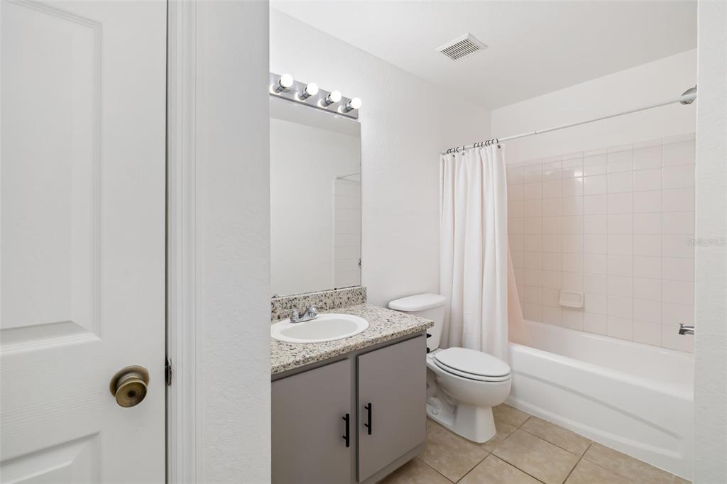 8933 Manor Loop, Unit 205 Lakewood Ranch, FL 34202 - Photo 30 of 76 a bathroom with a toilet a sink a mirror a bathtub and shower