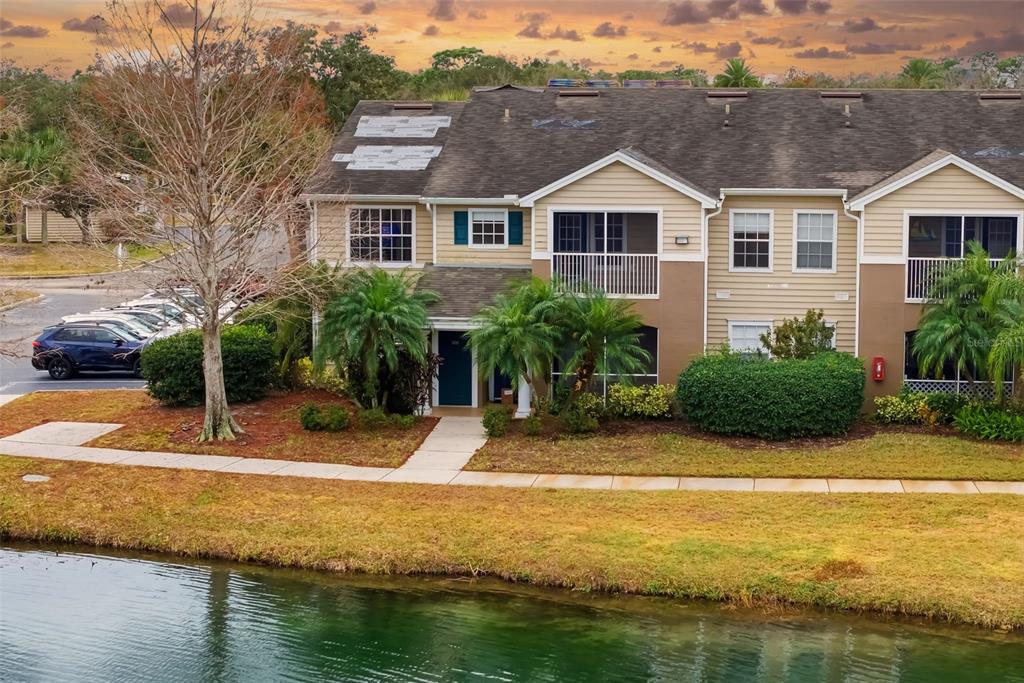8933 Manor Loop, Unit 205 Lakewood Ranch, FL 34202 - Photo 46 of 76 a view of a white house with a swimming pool and lawn chairs under an umbrella