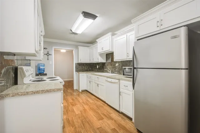 a kitchen with stainless steel appliances granite countertop a refrigerator a stove a sink dishwasher and a refrigerator with wooden floor