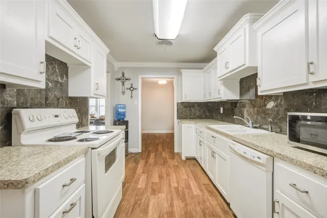 a kitchen with stainless steel appliances granite countertop a white stove top oven a sink dishwasher and white cabinets with wooden floor