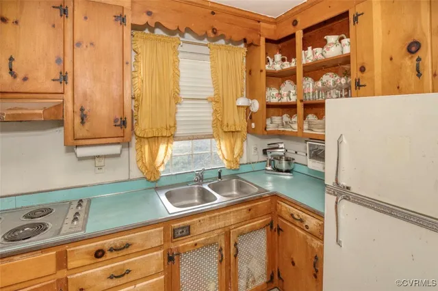 a kitchen with a refrigerator a stove top oven a sink and a window