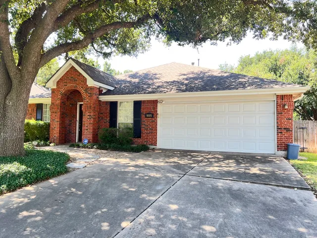 a view of a house with a yard and large tree