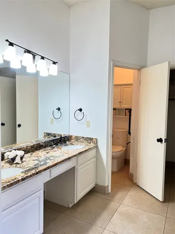 a en suite bathroom with a granite countertop sink and a mirror