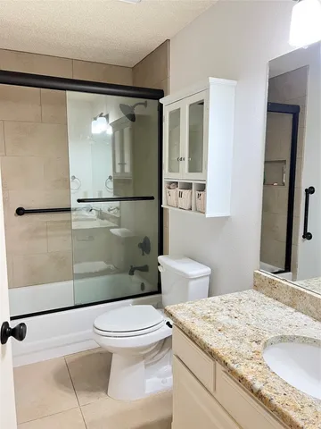 a bathroom with a granite countertop sink mirror vanity and toilet