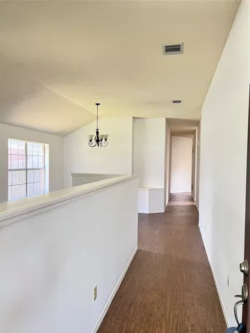 a view of a hallway with wooden floor and cabinet