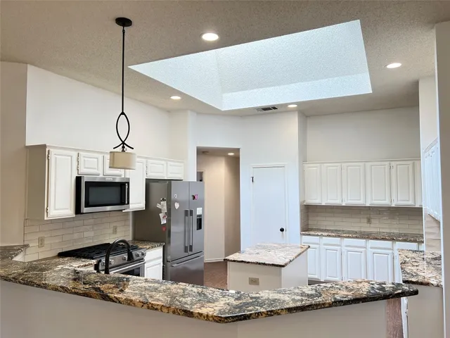 a kitchen with stainless steel appliances granite countertop a sink refrigerator and microwave