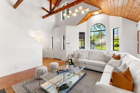 a living room with kitchen island furniture a chandelier and kitchen view