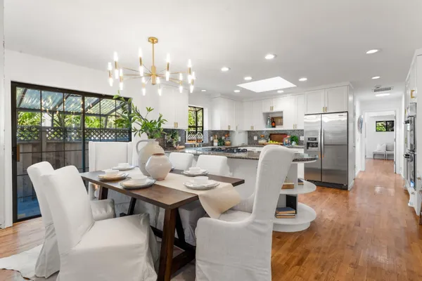a dining room with furniture wooden floor and a kitchen view