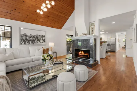 a living room with furniture a fireplace and a dining room with wooden floor