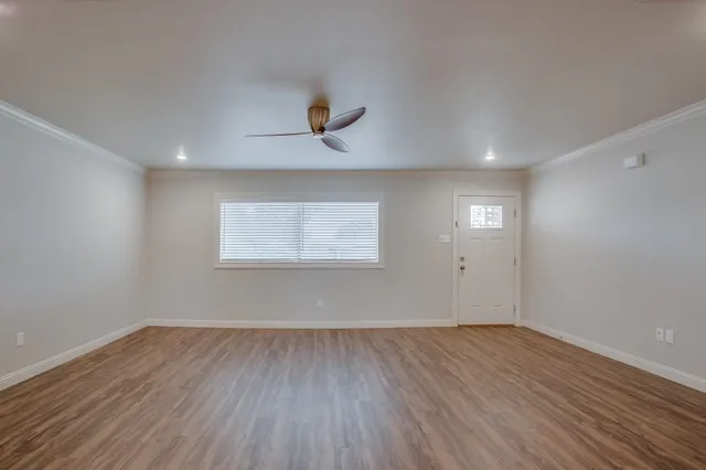 a view of an empty room with wooden floor and a window