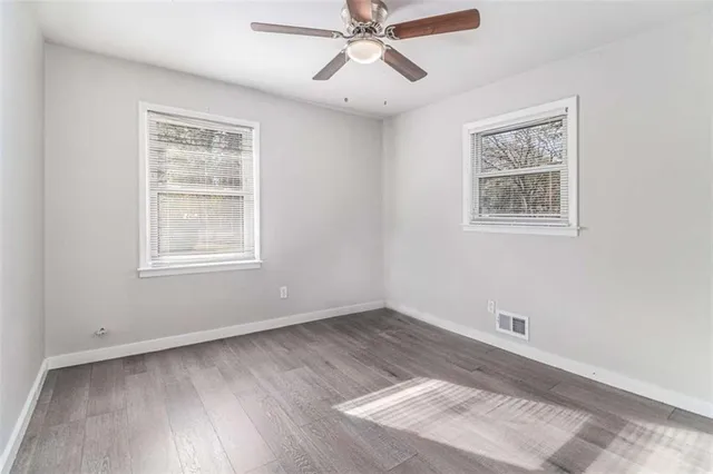 a view of an empty room with a window and wooden floor