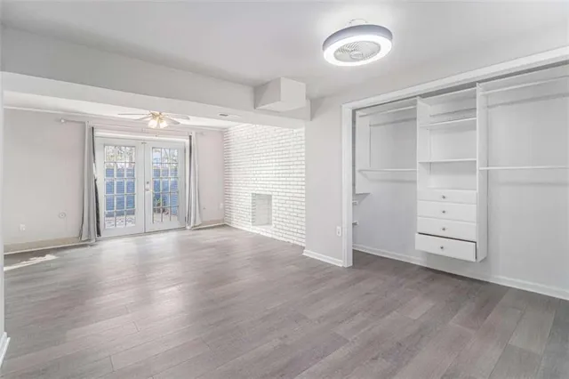 an empty room with wooden floor cabinet and windows