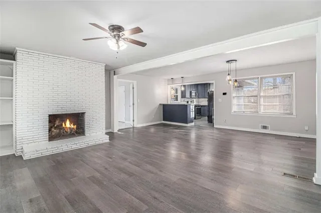 a view of an empty room with a fireplace and wooden floor