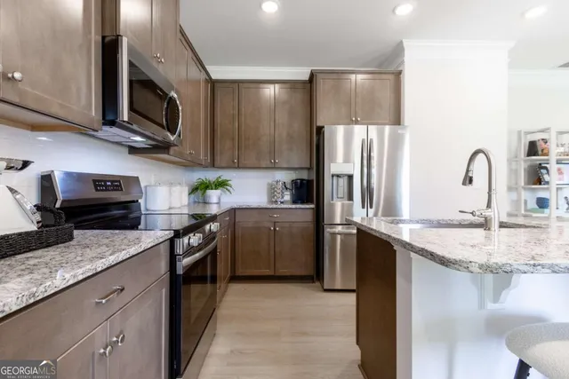 a kitchen with stainless steel appliances granite countertop a sink stove microwave and refrigerator