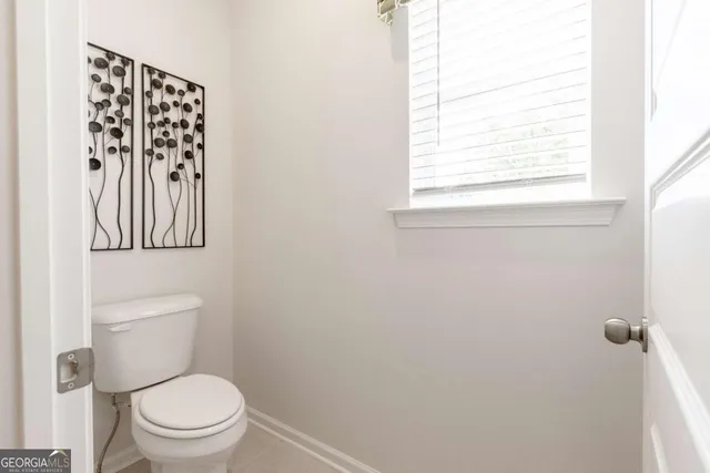 a white toilet sitting next to a window in a bathroom