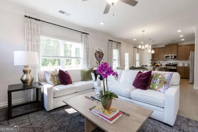 a living room with furniture flowers and a large window