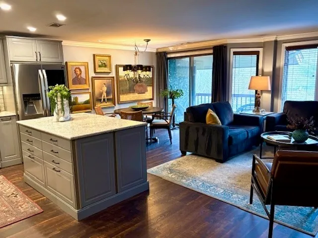 a living room with stainless steel appliances kitchen island granite countertop furniture a large window and a sink