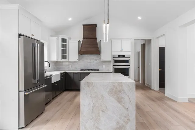 a large kitchen with a refrigerator a sink a stove and cabinets