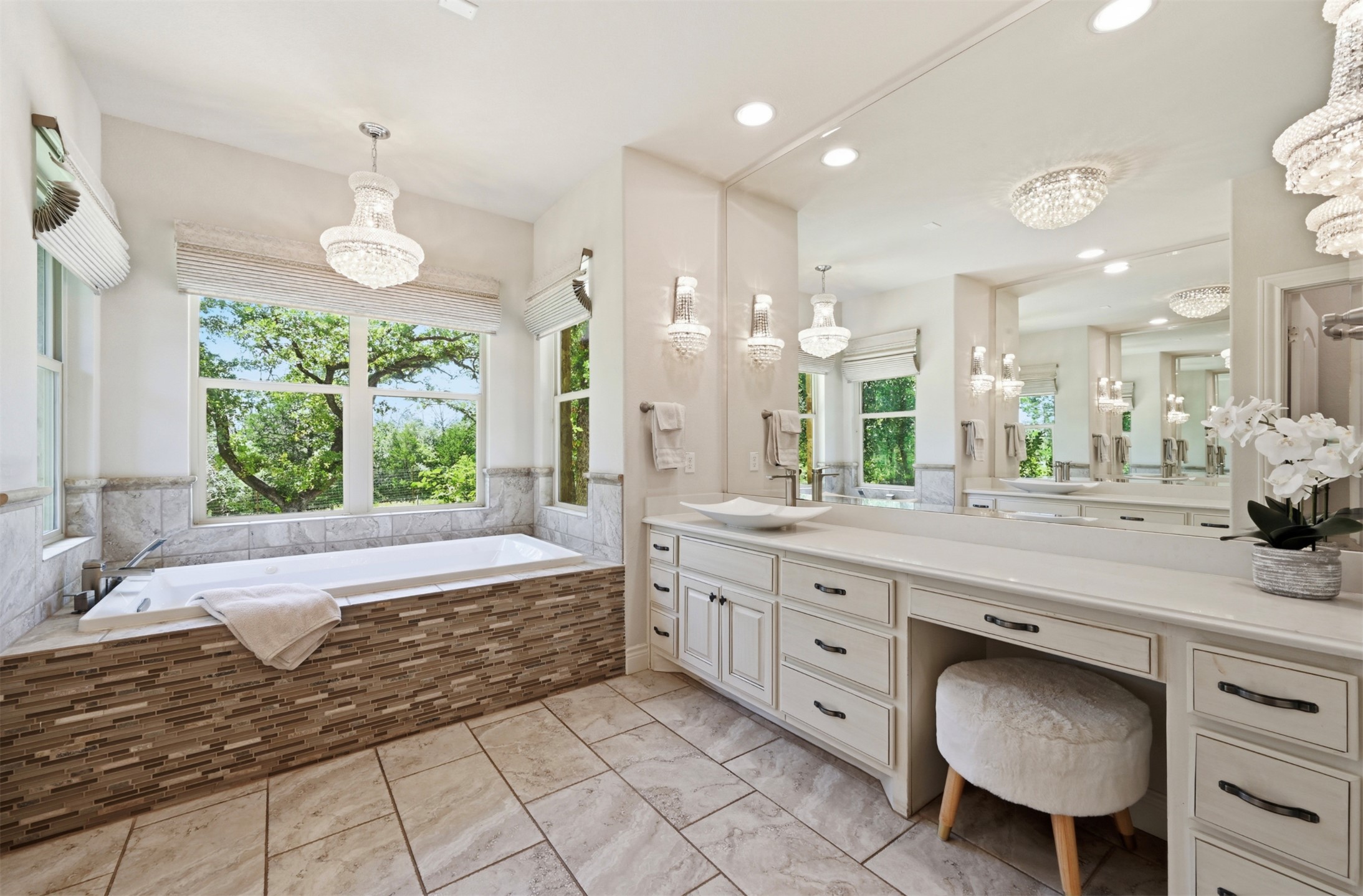 387 Corral Road Smithville, TX 78957 - Photo 18 of 40 Spacious bathroom featuring a built-in soaking tub with mosaic tile surround, dual vanities with integrated sinks, and ample storage cabinetry