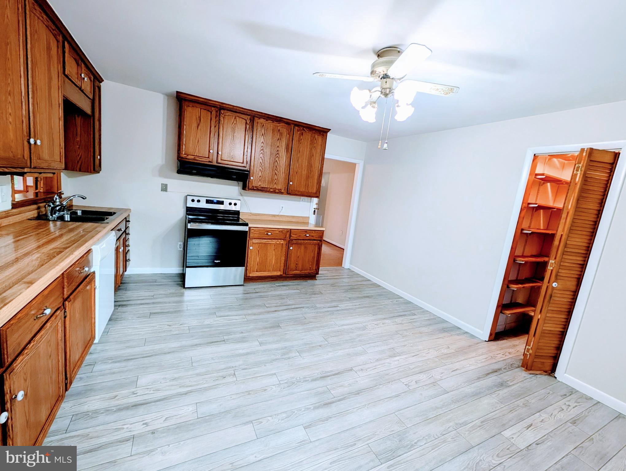 7403 Bear Branch Road Adamstown, MD 21710 - Photo 5 of 43 a kitchen with stainless steel appliances a stove top oven a sink dishwasher and a microwave oven with wooden floor