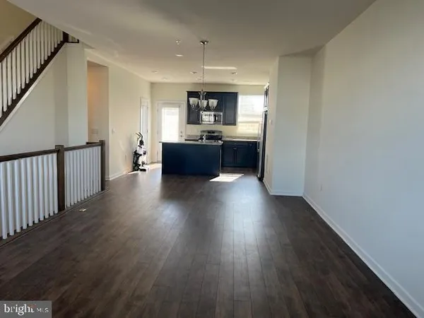 a living room with wooden floors and kitchen view