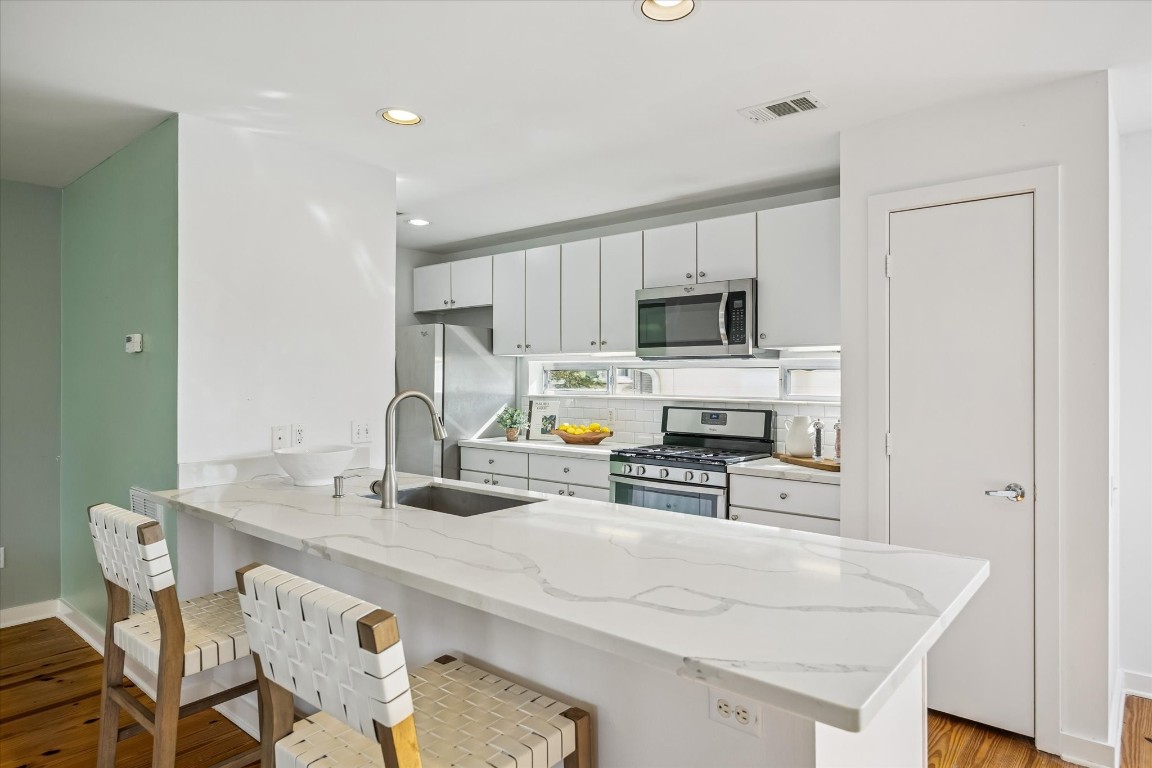 2508 Calumet Street, Unit E Houston, TX 77004 - Photo 7 of 31 a kitchen with stainless steel appliances a stove a sink a microwave a refrigerator and cabinets