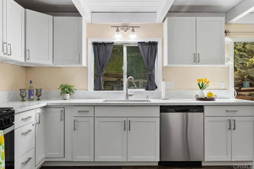 921 Lemon Avenue Vista, CA 92084 - Photo 11 of 32 a kitchen with white cabinets a sink and dishwasher next to a window