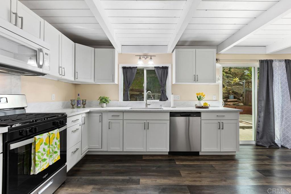 921 Lemon Avenue Vista, CA 92084 - Photo 12 of 32 a kitchen that has a lot of white cabinets and wooden floor