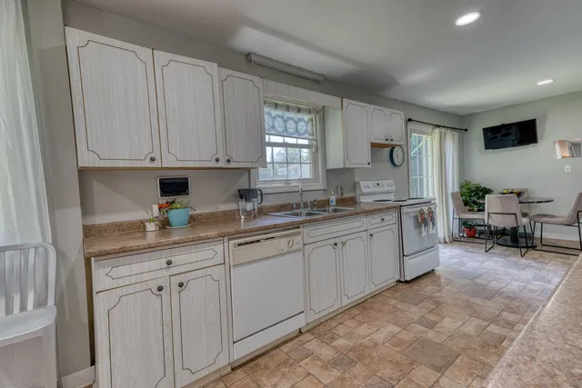 a kitchen with granite countertop white cabinets sink and dishwasher with a large window
