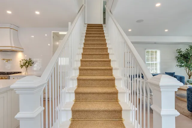 a view of staircase with lots of frames on wall and a chandelier